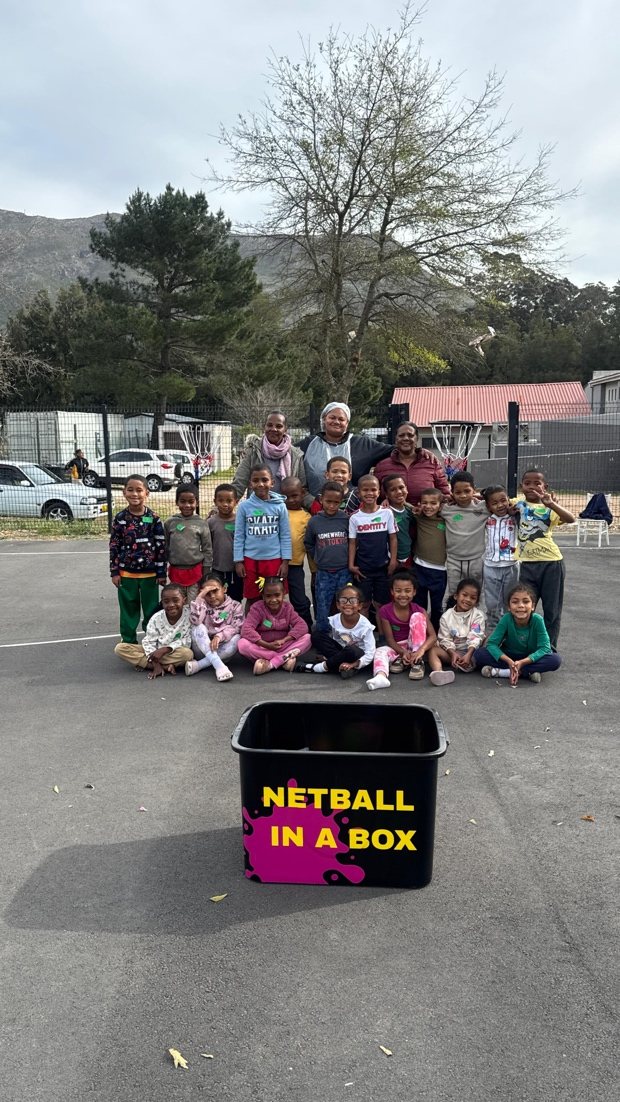 Learners and staff gathered behind the Netball in a Box crate with mountains in the background