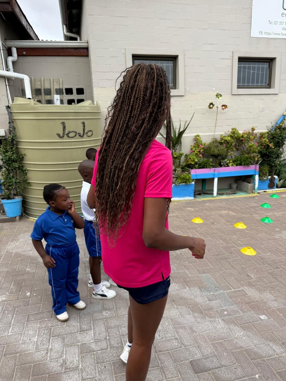 A DSL coach with children at the netball cone stations at Ubunye Educare Centre