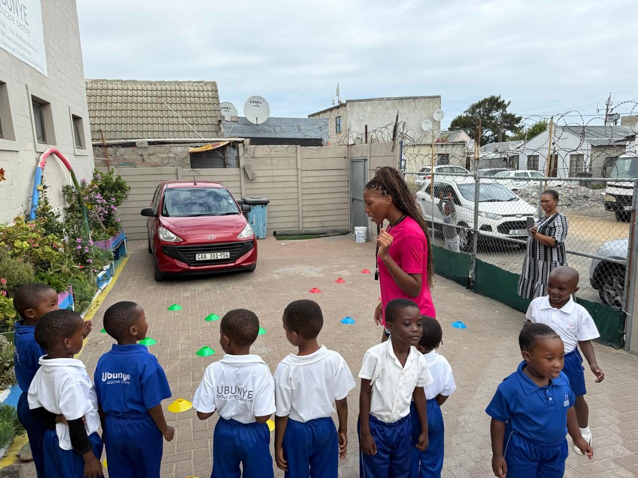 A DSL coach explaining a netball drill to a line of Ubunye Educare Centre children