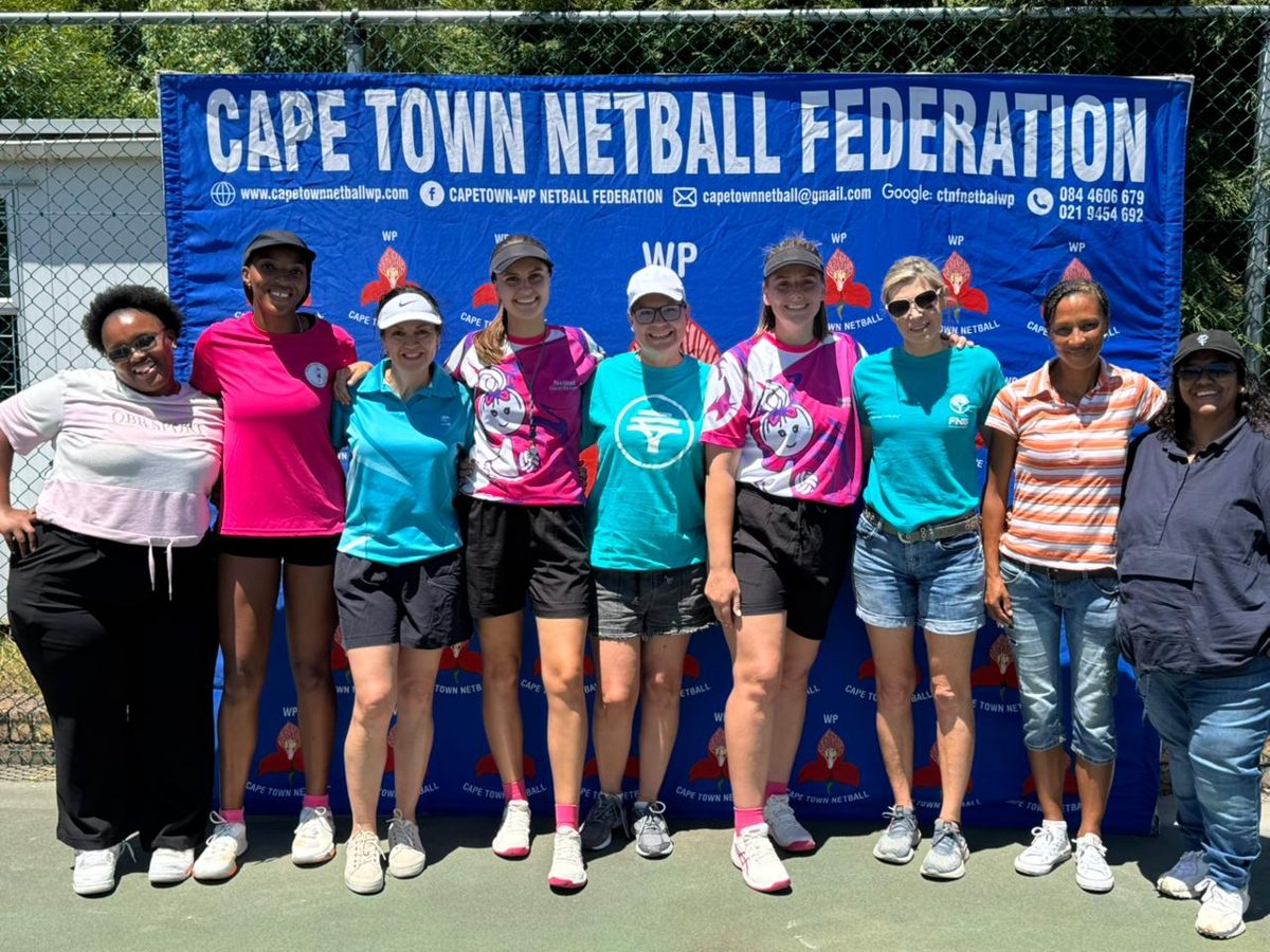A group of DSL and FNB Care volunteers in front of a Cape Town Netball Federation banner