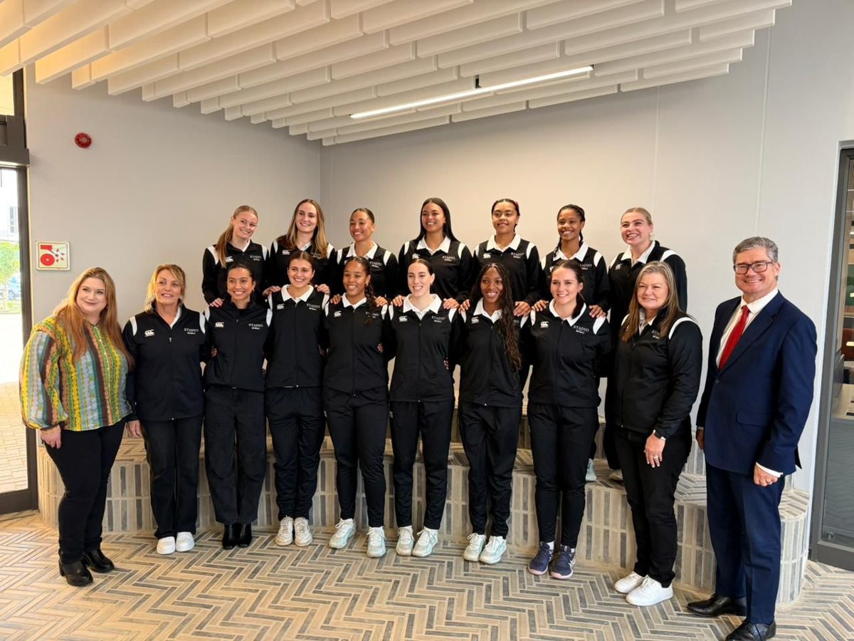 The STADIO Ladies 1st Team and STADIO staff standing together indoors
