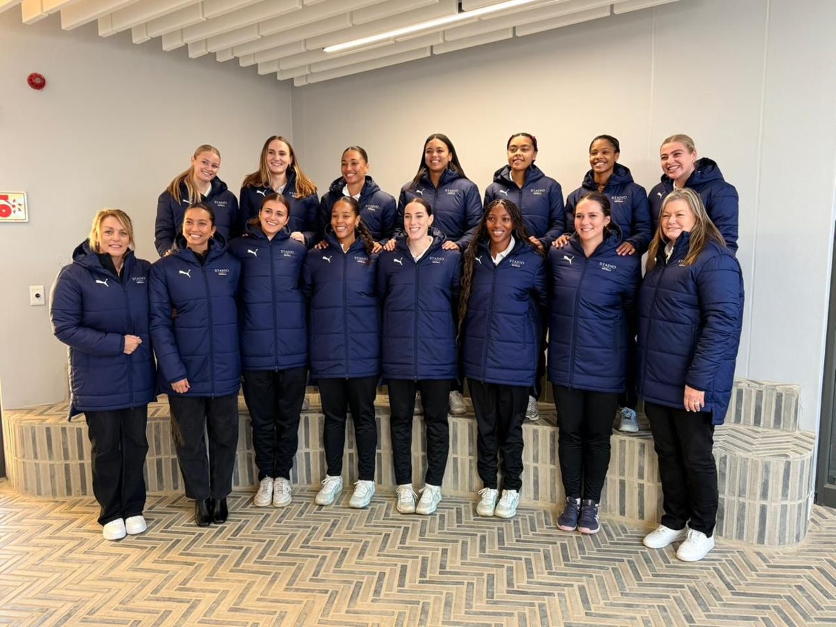 The STADIO Ladies 1st Team in navy jackets standing together indoors