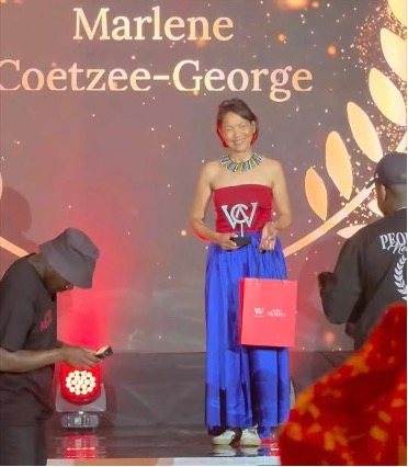 Marlene Coetzee-George on stage holding her SheCAN award